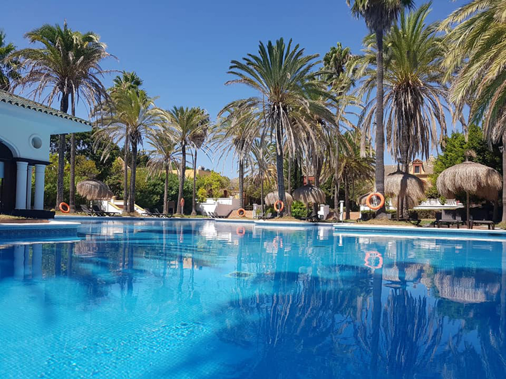 Palm-lined pool and traditional architecture at San Roque Club